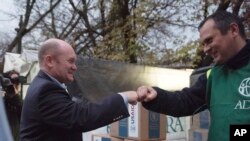 El senador estadounidense Chris Coons, a la izquierda, saluda a un voluntario durante su visita a un centro de distribución de la Agencia de Estados Unidos para el Desarrollo Internacional en Kiev, Ucrania, el jueves 3 de noviembre de 2022.