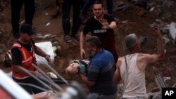 Palestinos cargan a un niño muerto encontrado bajo los escombros de un edificio destruido tras los ataques aéreos israelíes en el campo de refugiados de Nuseirat, en el centro de la Franja de Gaza, el 31 de octubre de 2023.