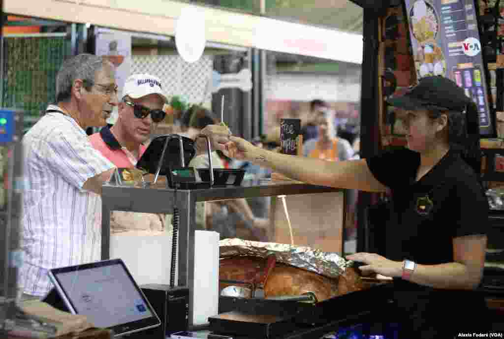 María Paula Solina ofrece una muestra de su producto a clientes ocasionales que se acercan al puesto de venta, en el&nbsp;Yellow Green Farmers Market, en Hollywood, Florida, el sábado 10 de junio de 2023.&nbsp;