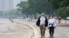 People walk along the shoreline of Lake Michigan with heavy smoke from the Canadian wildfires in the background, on June 27, 2023, in Chicago.