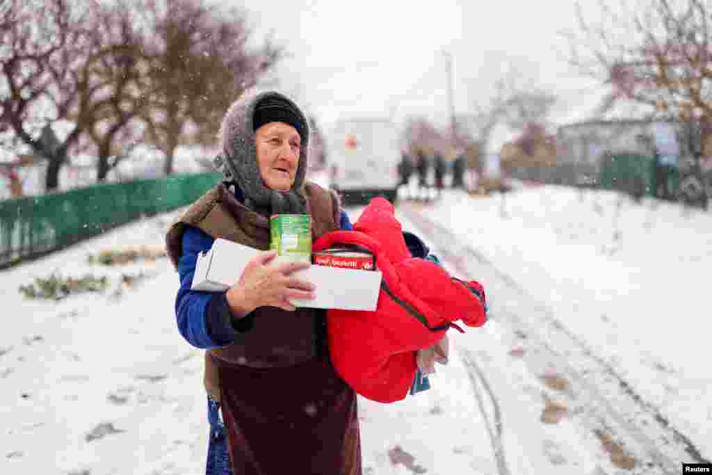 Valentina, de 76 años, lleva comida y ropa que le han dado voluntarios cerca de Jersón, Ucrania, el 29 de enero de 2023.&nbsp;