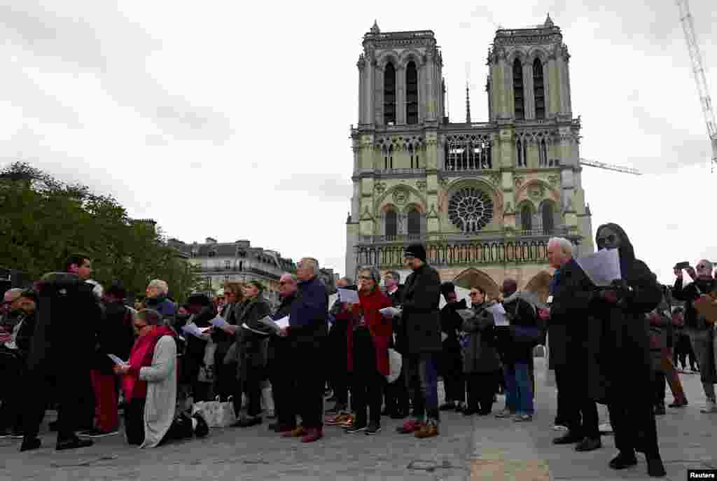 La gente asiste a una procesión del "Via Crucis" del Viernes Santo cerca de la Catedral de Notre-Dame de París en París, Francia.