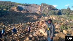People gather at the site of a landslide in Maip Mulitaka in Papua New Guinea's Enga Province on May 24, 2024. Local officials and aid groups said a massive landslide struck a village in Papua New Guinea's highlands on May 24, with many feared dead. 