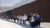 Un grupo de personas, entre ellas muchas de China, caminan a lo largo del muro después de cruzar la frontera con México para buscar asilo, cerca de Jacumba, California, el 24 de octubre de 2023.