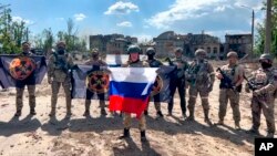 In this handout photo taken from video and released by Prigozhin Press Service May 20, 2023, Yevgeny Prigozhin, the head of the Wagner Group military company speaks holding a Russian flag in front of his soldiers in Bakhmut, Ukraine. 