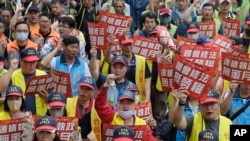 แรงงานไต้หวันถือป้ายสโลแกนประท้วงวันแรงงานที่กรุงไทเป เมื่อ 1 พ.ค. 2024 (AP Photo/Chiang Ying-ying)