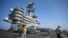 El personal de la cabina de vuelo pasa frente a los aviones a bordo del portaaviones USS GW Bush que navega en el mar Mediterráneo, el lunes 17 de octubre de 2022.