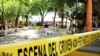 ARCHIVO - En esta fotografía de archivo del 10 de marzo de 2015, el cuerpo cubierto del un periodista yace en el suelo en el parque central de Mazatenango, Guatemala. 
