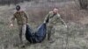 Miembros de un equipo ucraniano especial retiran los restos de un soldado ruso encontrado en la aldea de Synykha, en la región de Járkov, el 8 de abril de 2023.