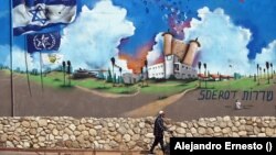 Un anciano camina junto a un mural pintado en lo que fue la estación de policía de Sderot totalmente destruida durante el ataque de Hamás.