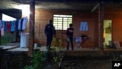 ARCHIVO - En esta fotografía publicada por la Policía Civil brasileña, agentes en el porche de una casa donde fue rescatada la madre del futbolista brasileño Taison, en Brasil, el 16 de julio de 2018.