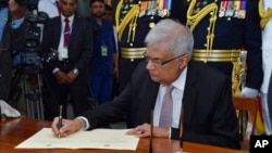 En esta foto proporcionada por la oficina del presidente de Sri Lanka, el recién elegido presidente de Sri Lanka, Ranil Wickremesinghe, firma después de prestar juramento durante su ceremonia de investidura en Colombo, Sri Lanka, el 21 de julio de 2022.