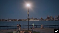 ARCHIVO - La gente pasa tiempo en el parque al anochecer durante una ola de calor de verano, el 21 de julio de 2022, en Hoboken, Nueva Jersey.