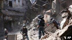 Empleados del Ministerio de Situaciones de Emergencia de la República Popular de Donetsk limpian los escombros al costado del edificio del teatro Mariupol dañado durante los intensos combates en Mariupol, en territorio bajo el gobierno de la República Popular de Donetsk, este de Ucrania, el 1 de mayo de 2022.