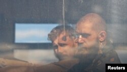 Miembros del servicio de las fuerzas ucranianas que se han rendido después de semanas escondidos en la acería de Azovstal se ven dentro de un autobús que se aleja escoltado por el ejército prorruso en el conflicto Ucrania-Rusia en Mariúpol, Ucrania, el 17 de mayo de 2022.