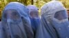 Mujeres afganas con burkas se detienen en una calle del este de Kabul mientras el grupo "La Coalición General de Mujeres" organizaba una reunión de mujeres afganas para manifestarse por sus derechos el 20 de noviembre de 2001.