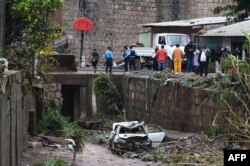 Oficiales de la Policía Nacional y lugareños observan los daños causados por las fuertes lluvias en Tegucigalpa, el 20 de mayo de 2022.