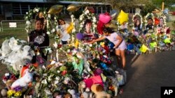 Aaliyah Banda, de 11 años, coloca un brazalete frente a la foto de Uziyah García, una de las víctimas del tiroteo en la escuela de la semana pasada, en un memorial en la Escuela Primaria Robb en Uvalde, Texas, el 31 de mayo de 2022.