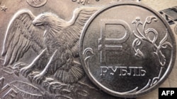 Una moneda de rublo ruso vista junto a billetes de dólares estadounidenses y una moneda de un dólar en Moscú, el 15 de marzo de 2022.