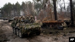 Soldados ucranianos captados el 31 de marzo mientras transitaban sobre vehículos blindados junto a un tanque ruso destruido en las afueras de Kiev. Alemania y otros países europeos refuerzan la ayuda al ejército del país invadido por Rusia.