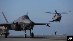 ARCHIVO - Personal militar dirige aviones F-35 y un helicóptero en la cubierta del portaaviones HMS Queen Elizabeth mientras participa en el ejercicio Steadfast Defender 2021 de la OTAN frente a las costas de Portugal, el 27 de mayo de 2021.