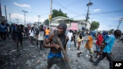 Un manifestante porta un pedazo de madera como si fuera un rifle durante una protesta antigubernamental, el 3 de octubre del 2022, en Puerto Príncipe, Haití. (AP Foto/Odelyn Joseph)