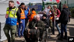 Voluntarios ayudan a los refugiados en silla de ruedas después de huir de la guerra desde la vecina Ucrania en el cruce fronterizo de Medyka, sureste de Polonia, el 11 de abril de 2022.
