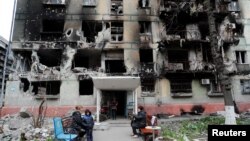 Los residentes se reúnen frente a un edificio residencial gravemente dañado durante la invasión rusa de Ucrania, en la ciudad portuaria sureña de Mariupol, el 21 de abril de 2022.