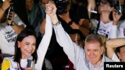 Edmundo González Urrutia, candidato presidencial de la Plataforma Unitaria en Venezuela, alza la mano junto a la dirigente María Corina Machado, en el acto de cierre de campaña en Caracas, el 25 de julio de 2024.