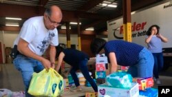 Personal de la organización caritativa Caridades Católicas en Rio Grande Valley, Texas, y voluntarios descargan cajas de donaciones en una bodega en McAllen. El grupo, que brinda lugar de descanso a los migrantes tuvo que alquilar espacio adicional para las donaciones y está recibiendo voluntarios de todo el país.