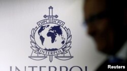 En la foto de archivo un hombre pasa un logotipo de Interpol durante la ceremonia de entrega de las nuevas instalaciones del Complejo Global para la Innovación de Interpol.