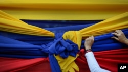 Una partidaria de la oposición sostiene una tela con los colores de la bandera venezolana antes de un mitin con el líder opositor Juan Guaidó en Caracas, el 11 de enero de 2020.