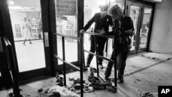 ARCHIVO - Un guardia de seguridad y otra persona no identificada miran el sitio donde varias personas murieron y otras resultaron heridas cuando quedaron atrapados en una multitud que ingresaba al Riverfront Coliseum de Cincinnati para un concierto de The Who el 3 de diciembre de 1979. (Foto AP/Brian Horton, archivo)