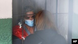 Tras las rejas, la expresidenta interina de Bolivia, Jeanine Áñez, habla con una mujer no identificada en la cárcel de una comisaría en La Paz, Bolivia, el 13 de marzo de 2021.
