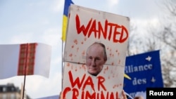 Una persona sostiene un cartel con una imagen del presidente ruso Vladimir Putin durante una protesta en el Reino Unido.