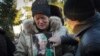La madre del escritor ucraniano Volodymyr Vakulenko sostiene su foto mientras llora cerca de su tumba durante una ceremonia fúnebre en Kharkiv, Ucrania, el 6 de diciembre de 2022.