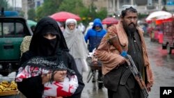 Un combatiente talibán hace guardia mientras la gente camina por el antiguo mercado, en la ciudad de Kabul, Afganistán, el martes 3 de mayo de 2022. (Foto AP/Ebrahim Noroozi)