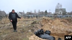 Un hombre muestra una fosa común con cadáveres en el poblado de Bucha, al noreste de Kiev, Ucrania, el 3 de abril de 2022.