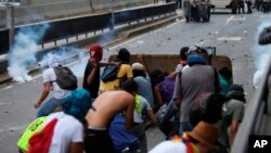 Los manifestantes lanzan piedras contra oficiales de la Policía Nacional Bolivariana durante una protesta en Caracas, Venezuela, el sábado 8 de abril de 2017.
