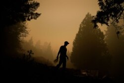 Aaron Cleys camina con un galón de agua tras combatir el fuego en una casa que fue destruida por el incendio Riverside, el viernes 11 de septiembre de 2020, en Estacada, Oregón.