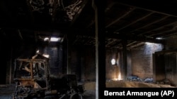 A tractor charred by a Russian attack lies inside a warehouse at a grain farm in Cherkaska Lozova, on the outskirts of Kharkiv, on May 28, 2022. (Bernat Armangue/AP)