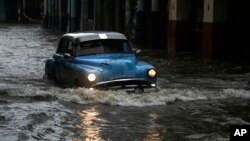 Una persona conduce un automóvil antiguo por una calle inundada por fuertes lluvias, en La Habana, Cuba, el viernes 3 de junio de 2022. (AP Foto/Ramon Espinosa)