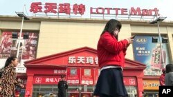 一名女子走在中国北京乐天超市前(2017年3月17日)