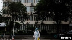 Un trabajador médico con traje protector cruza una calle tras un brote de la enfermedad del nuevo coronavirus en Beijing, el 6 de julio de 2022.