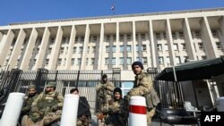 Fuerzas antigubernamentales hacen guardia frente al Banco Central de Siria en Damasco, el 9 de diciembre de 2024.