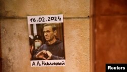 En la toma, una foto del líder opositor ruso Alexei Navalny pegada en una pared mientras la gente asiste a una vigilia tras su muerte en el Trocadero cerca de la Torre Eiffel en París, Francia, el 19 de febrero de 2024.