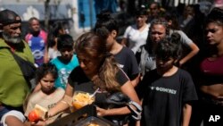 ARCHIVO: Personas reciben comidas calientes gratuitas en un comedor comunitario dirigido por el Movimiento de Trabajadores Excluidos (MTE) en Buenos Aires, Argentina, el viernes 8 de marzo de 2024.