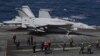 Un F-18 Super Hornet de la Marina de EEUU y miembros de la tripulación se ven en la cubierta de vuelo del USS Nimitz frente a la costa de Busan, Corea del Sur, el lunes 27 de marzo de 2023.