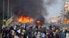Manifestantes contra el golpe militar se protegen detrás de una barricada en choques con las fuerzas de seguridad en un puente de Rangún, Myanmar, el 16 de marzo de 2021.
