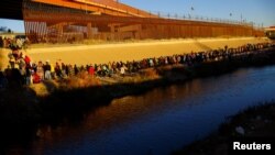 Migrantes hacen cola cerca del muro fronterizo después de cruzar el río Bravo para entregarse a los agentes de la Patrulla Fronteriza de EEUU para solicitar asilo en El Paso, Texas, visto desde Ciudad Juárez, México, el 14 de diciembre de 2022. REUTERS/José Luis González